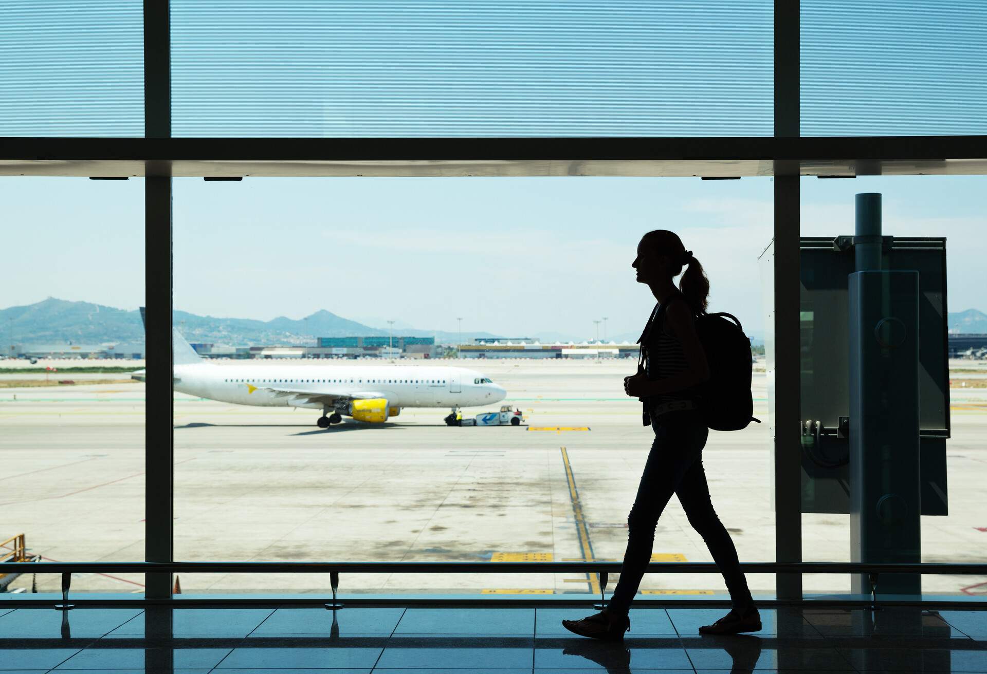 Silhouette of young woman walking at airport