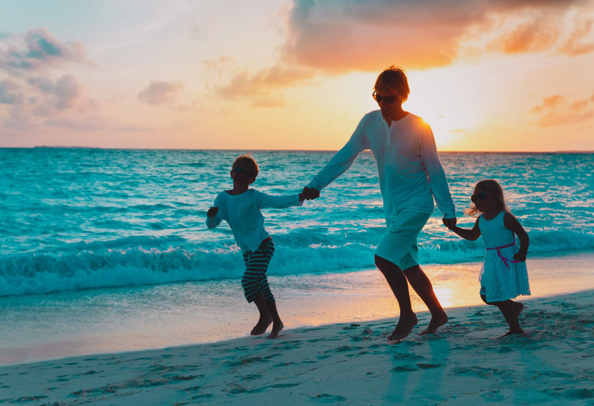 father and two kids play on beach at sunset; Shutterstock ID 1691166856; Purpose: email; Brand (KAYAK, Momondo, Any): kayak